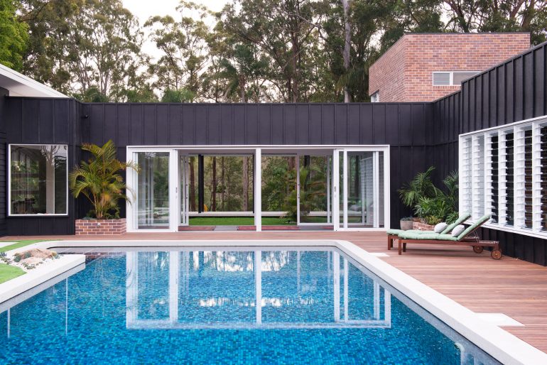 Home exterior overlooking outdoor pool and large windows