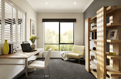 Modern home office with desk, laptop, chair by A&L ComfortSmart Hybrid Thermally Broken Sash window, yellow armchair, bookcase, neutral decor, and natural light.