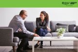 Two people seated on a gray sofa, talking and reviewing documents on a white coffee table, with a green banner and award logo above.